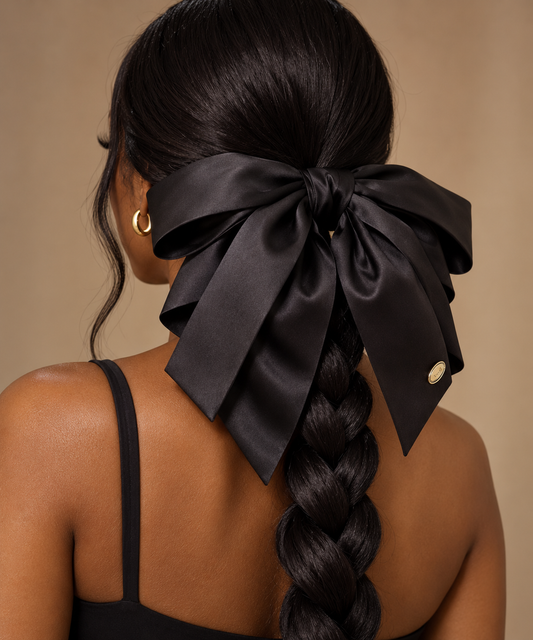 Black model wearing a black satin statement hair bow with long tails